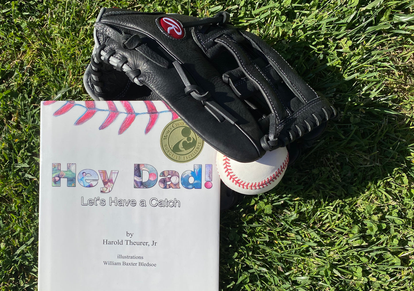 Photo of the book, with a black baseball glvoe and baseball. The book's cover says Hey Dad! in large print. In smaller print is "Let's have a Catch" by Harold Theurer Jr. Illustraions by William Baxter Bledsoe.