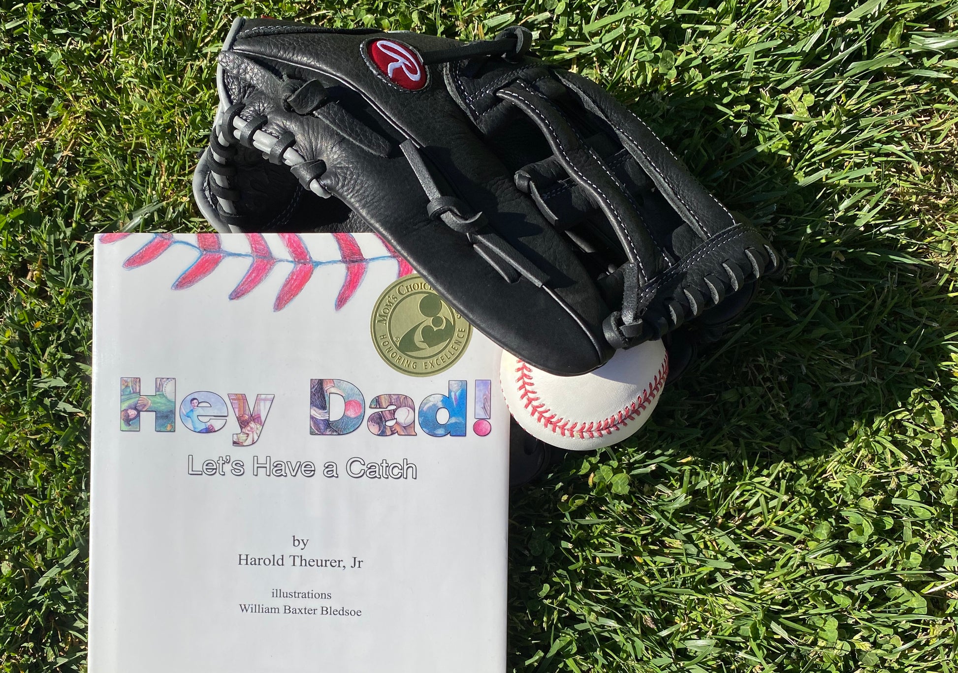 Photo of the book, with a black baseball glvoe and baseball.  The book's cover says Hey Dad! in large print.  In smaller print is "Let's have a Catch" by Harold Theurer Jr. Illustraions by William Baxter Bledsoe.